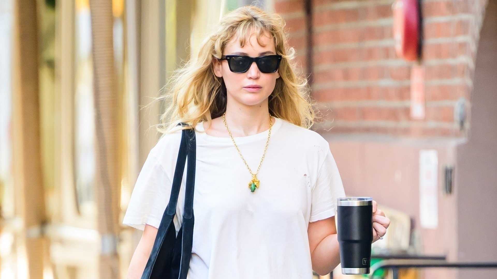 Jennifer Lawrence wearing a white T-shirt, low-rise bootcut jeans, and black tote, and black ballet flats in NYC