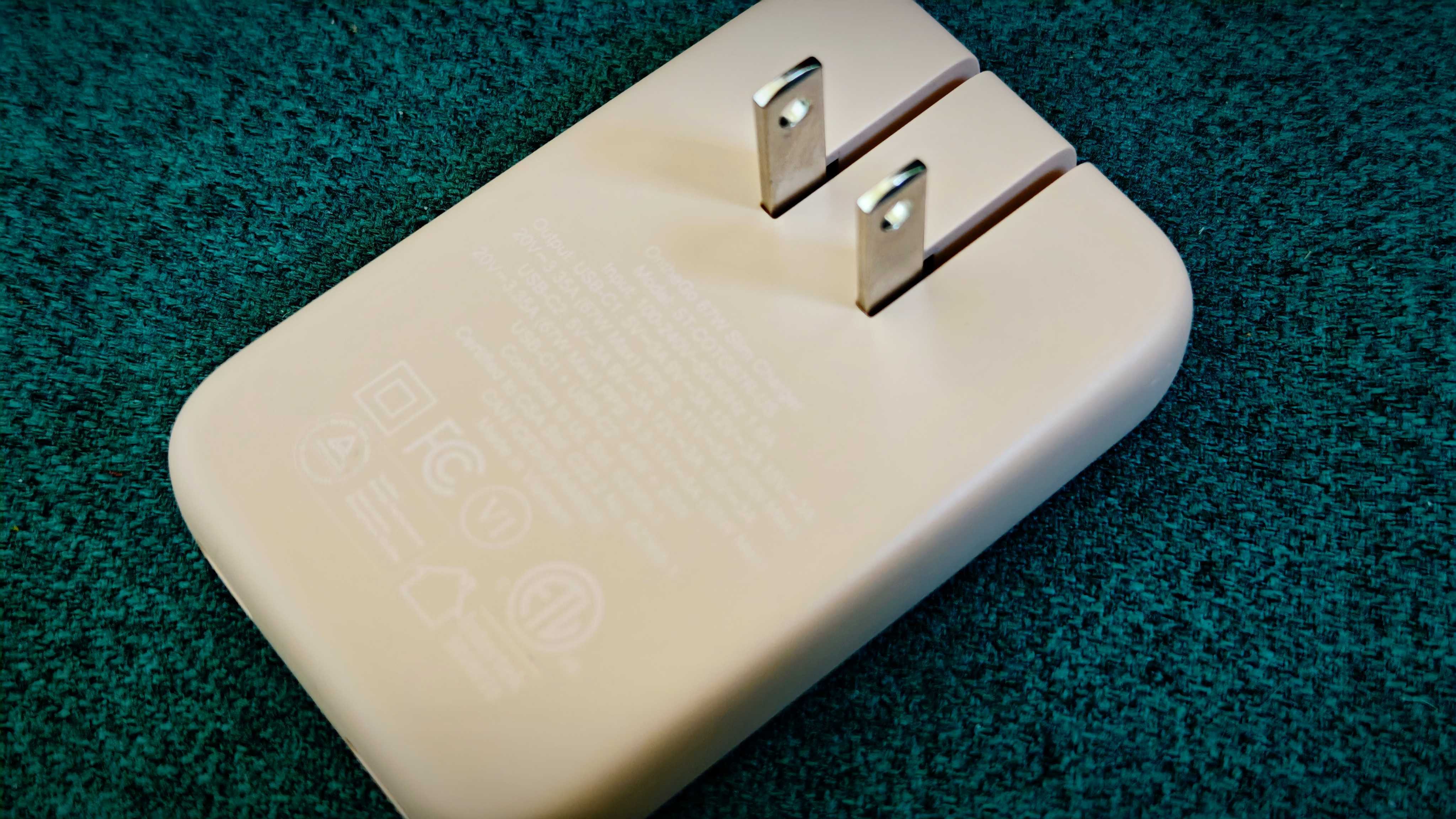 A Desert Rose coloured Satechi OntheGo 67W Slim Wall Charger on a green fabric sofa