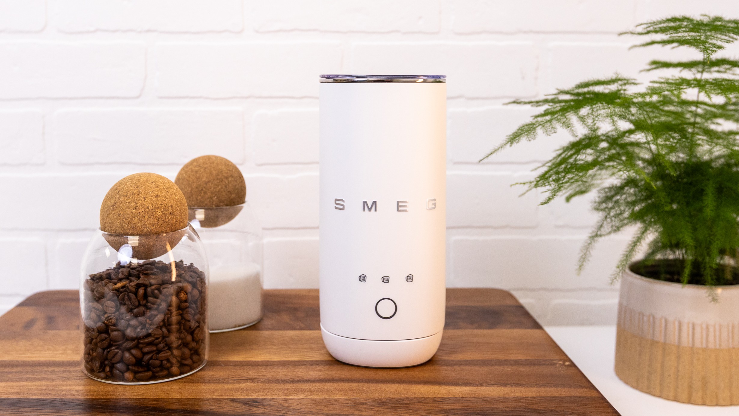 Smeg Mini Milk Frother on kitchen counter with coffee beans and sugar in jars