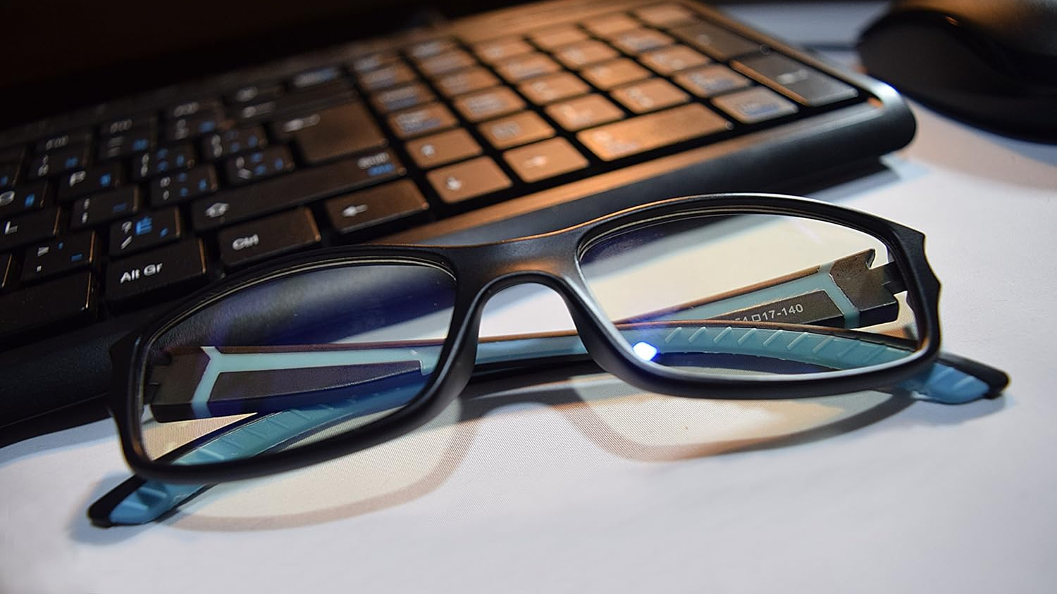 Prospek Gaming Glasses folded next to a keyboard