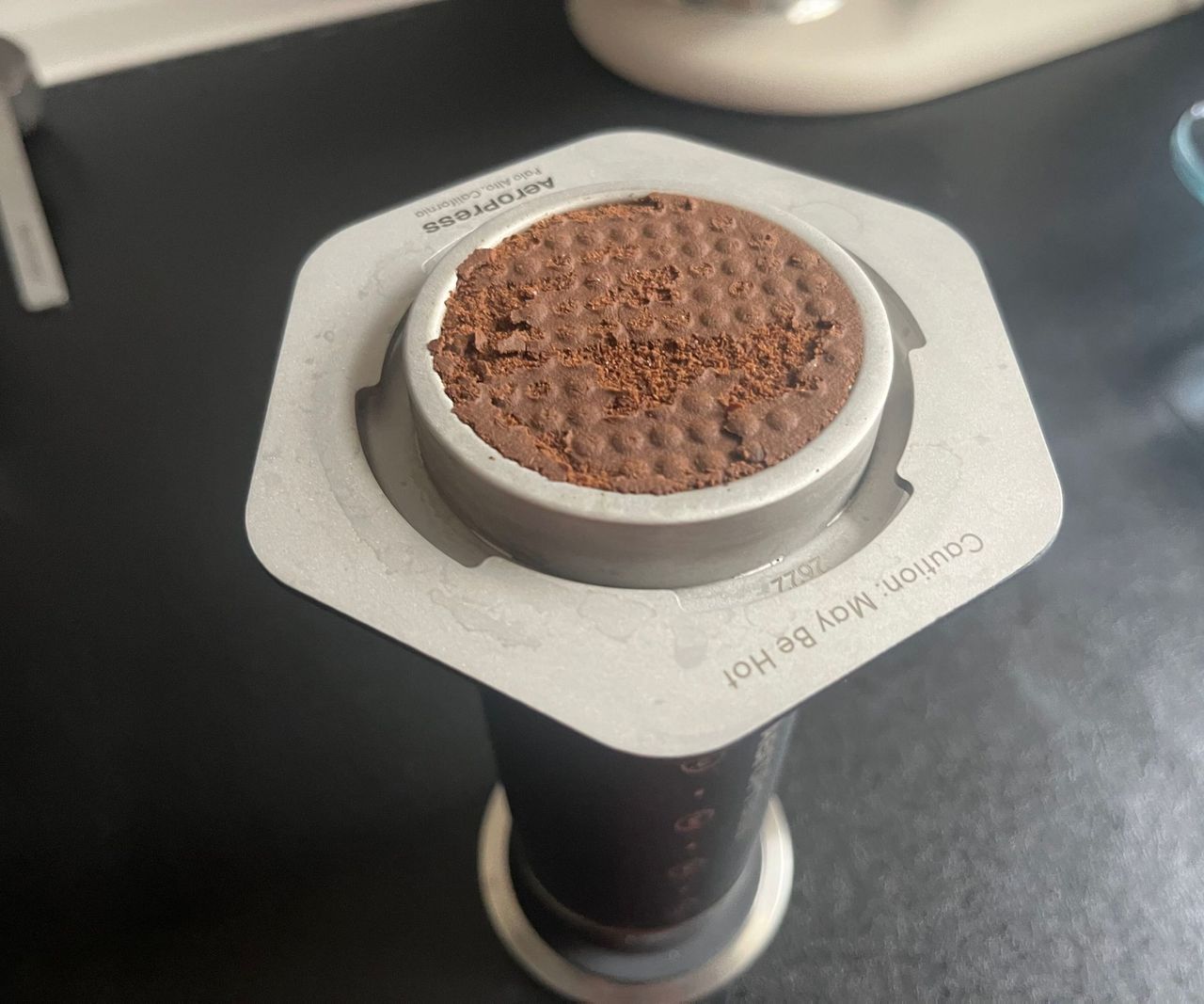 A AeroPress upside down with a coffee ground puck inside.