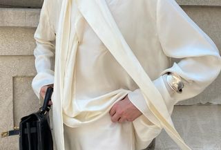 Christie Tyler wearing a cream silk scarf blouse with a lace-trim matching skirt.