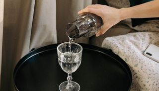 A hand pouring water into a glass