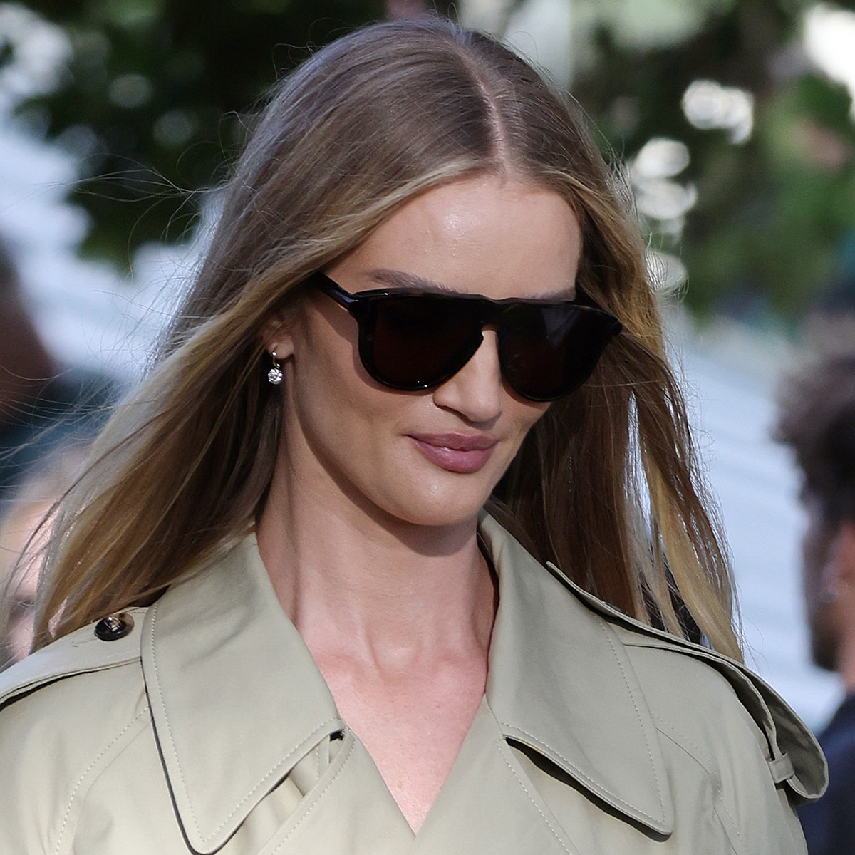 Rosie Huntington-Whiteley wears large sunglasses and a trench coat.
