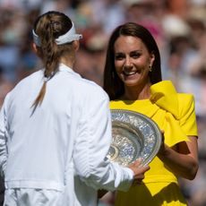 Kate Middleton in a yellow dress presenting a trophy to a tennis player