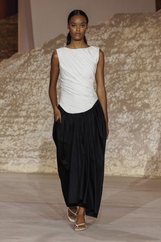 Seorang model mengenakan maxi dress berwarna putih dan hitam di runway Abadia