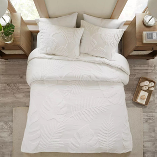 A white bedding set with chenille plant design