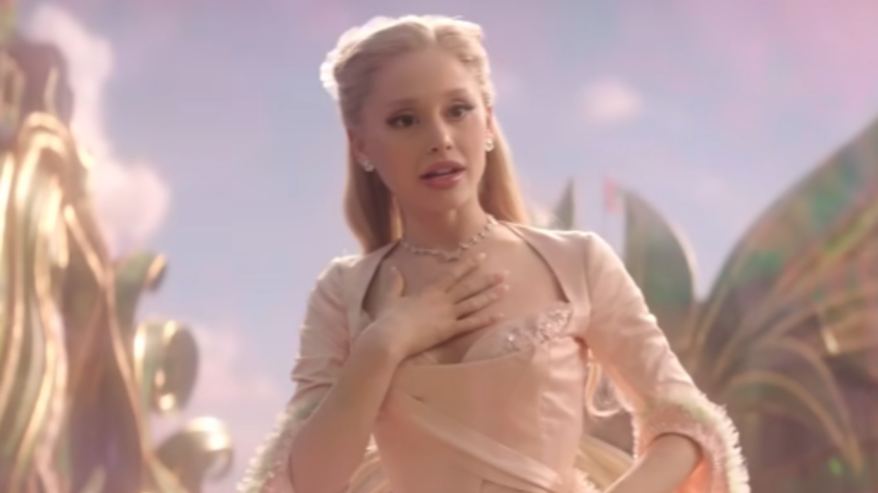 Ariana Grande as Glinda putting her left hand up to her heart in Wicked: For Good.