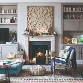 A light grey-painted living room with a fireplace and seating in front of it decorated for Christmas