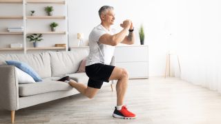 Man performs Bulgarian split squat, his rear leg is elevated on a sofa