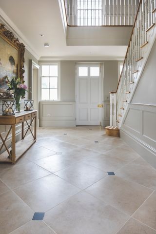 grand hallway with natural stone tiles, console table and painting