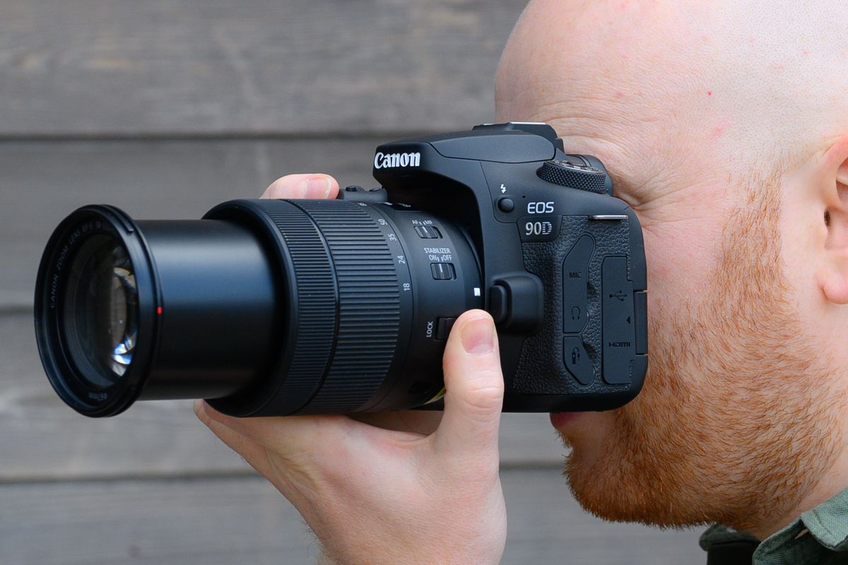 A hand holding the Canon EOS 90D camera