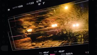 A monitor showing the muscle car-inspired Batmobile driving in wintry conditions
