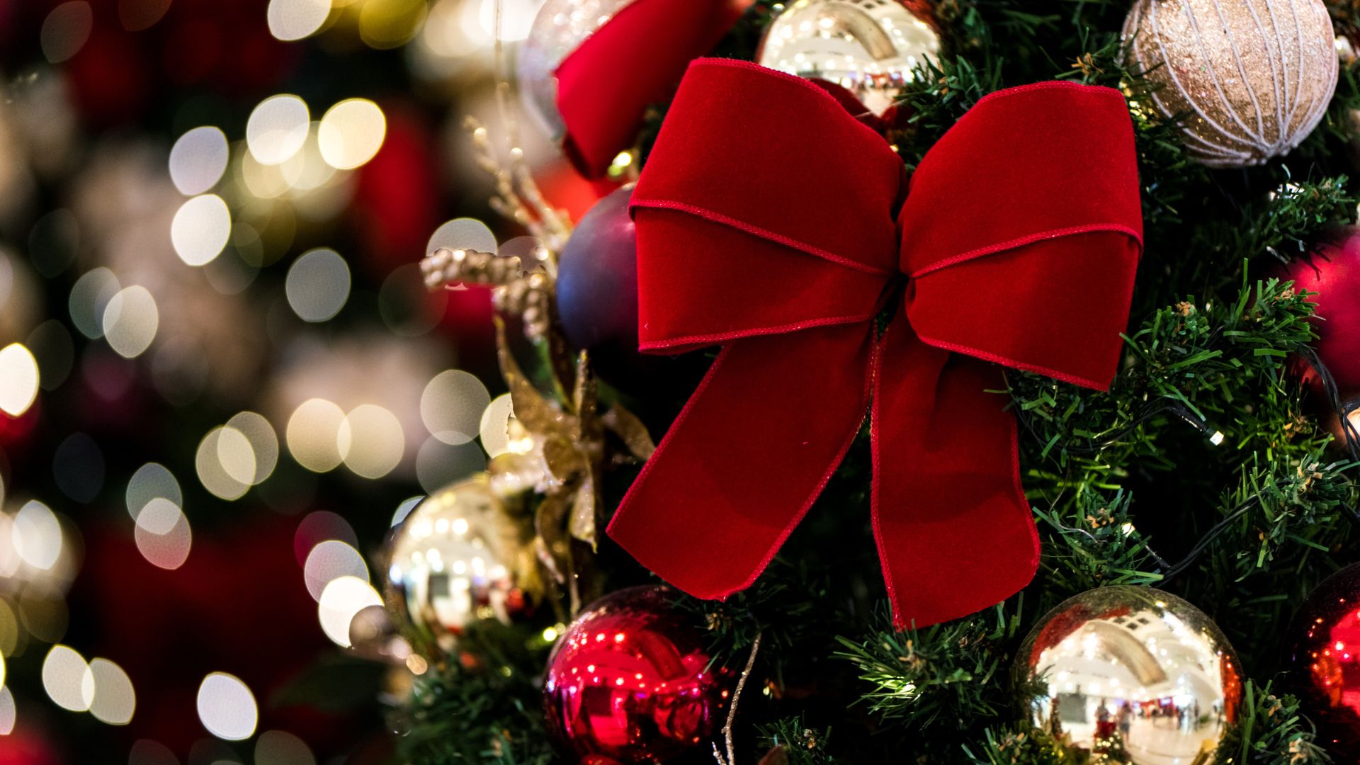 picture of red ribbon on christmas tree with gold baubles around it
