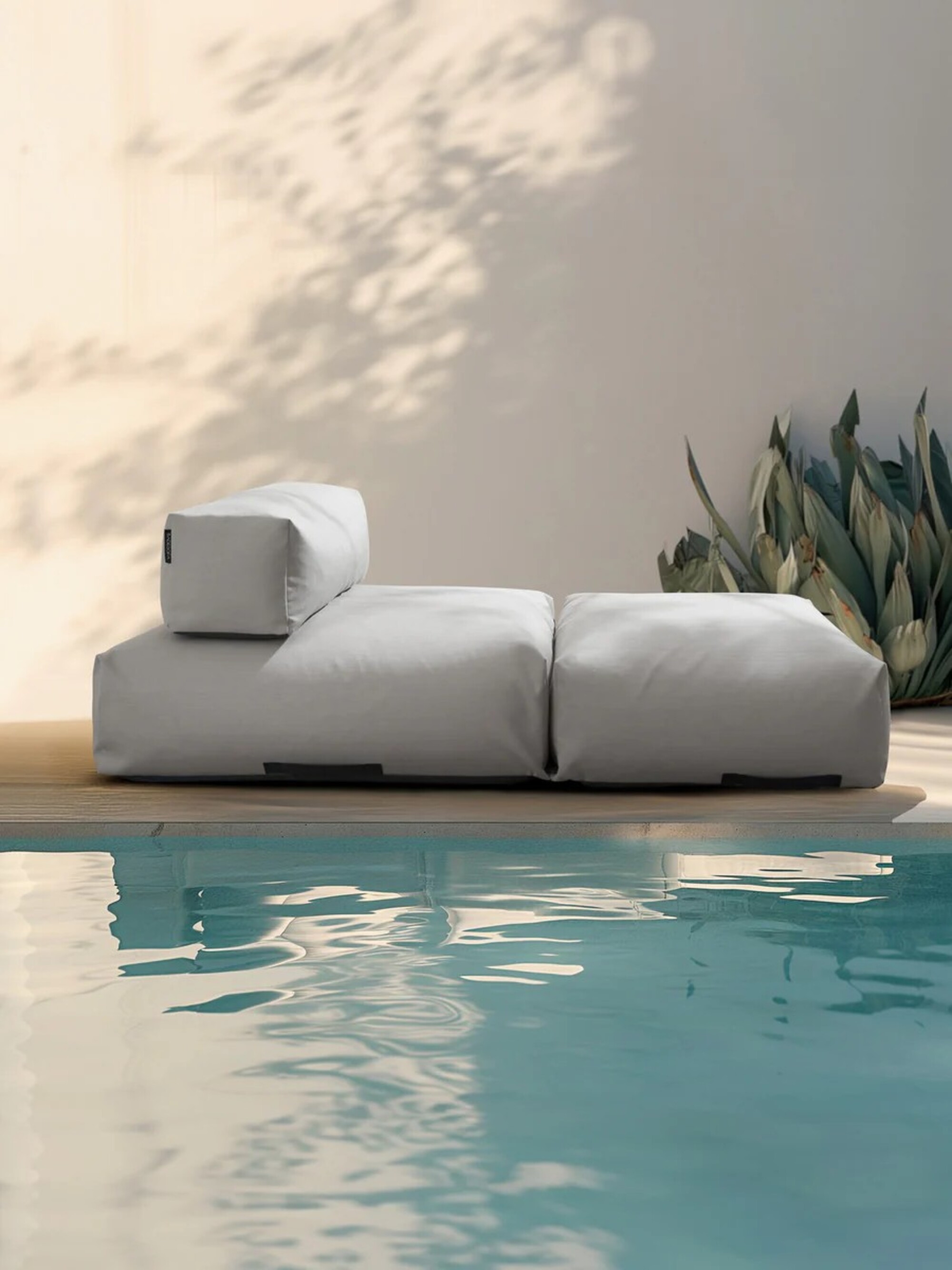 Image of a light gray pool lounger on a beige pool deck next to a pool.