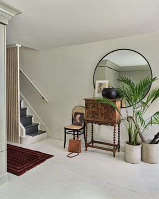 White hallway with vintage side table and circular mirror