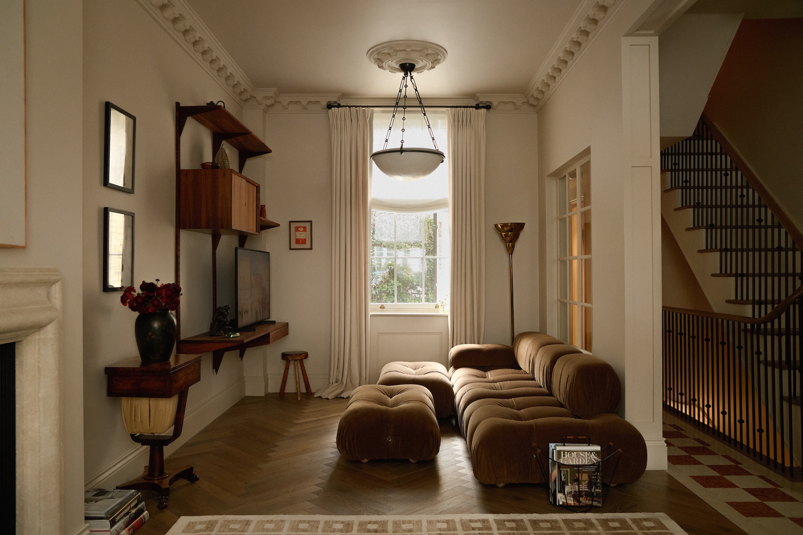 An open-plan living space with a velvet sofa with arms on one side and armless on the other
