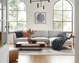 A grey chaise sofa in a modern living room with arched windows