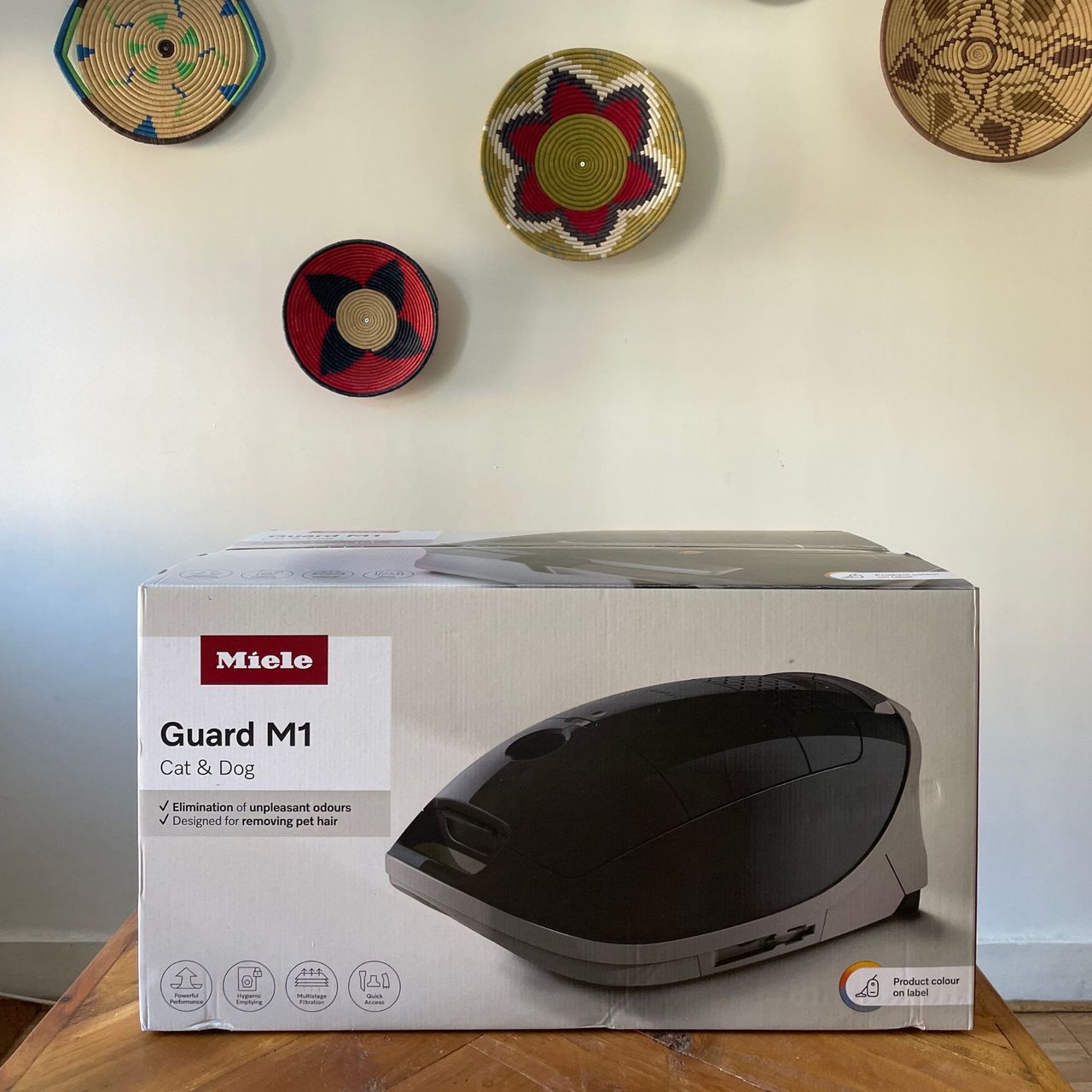 Miele Guard M1 Cat &amp; Dog box sitting on a wooden table in front of a white wall