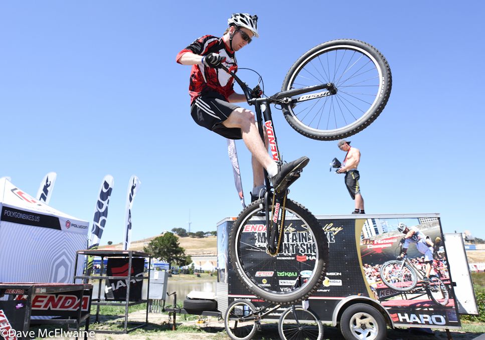 A stunt rider practices jumping a large gap while the short track race passed by.