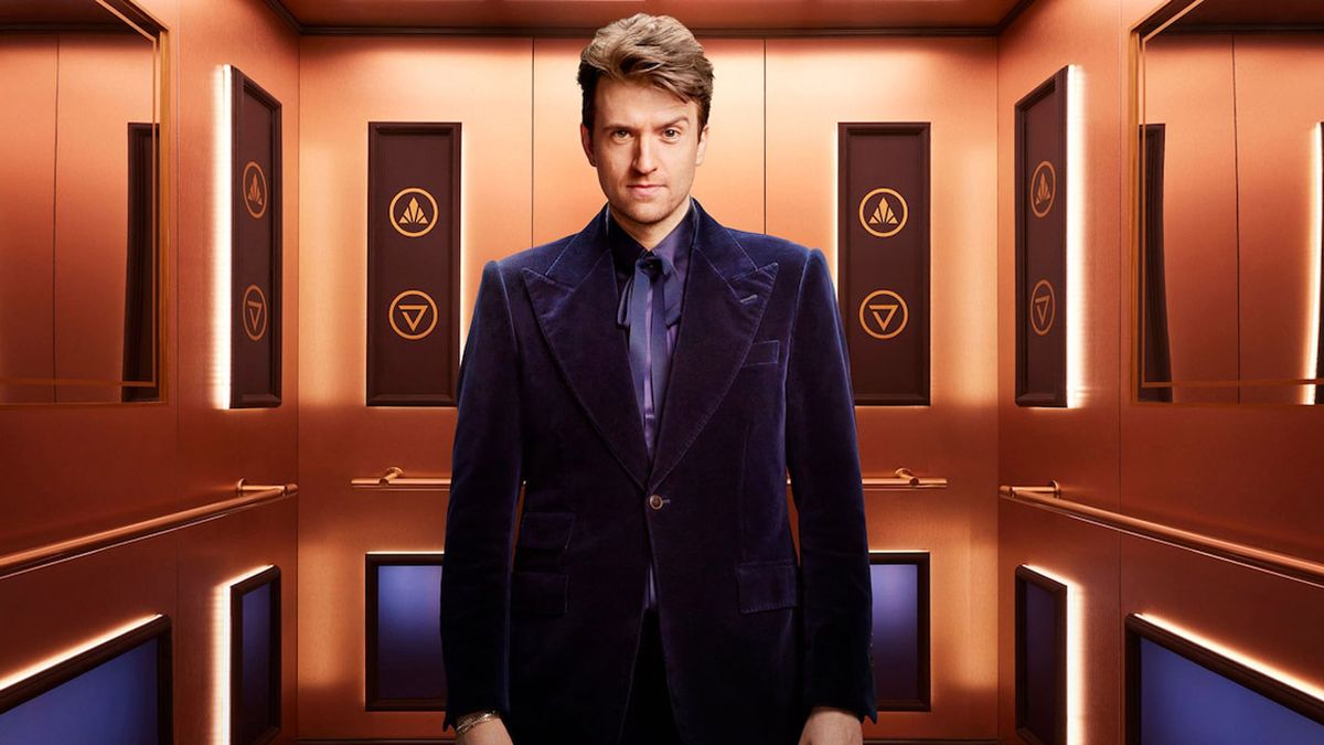 Greg James stands in the elevator of Rise and Fall