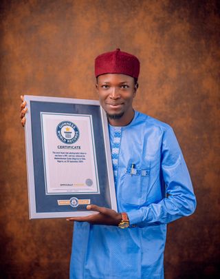 Photographer Saidu Abdulrahaman holds a framed Guiness Book of World Records certificate