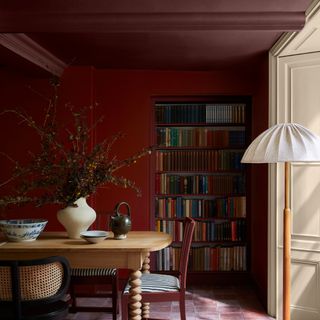 A double-drenched dining room with red walls and a darker burgundy ceiling