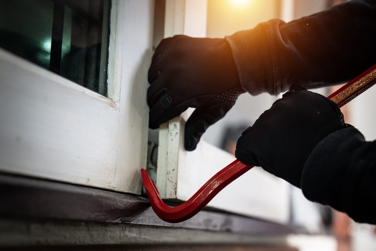 dangerous masked burglar with crowbar breaking into a victim&#039;s home door,concept