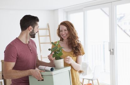 Young couple in new flat with cardboard boxes unpacking boxes