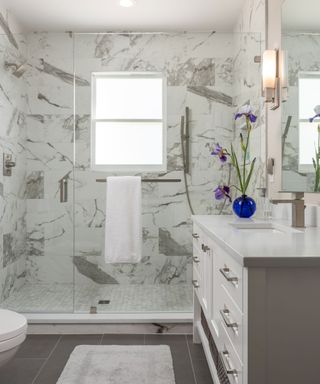 Neutral bathroom with obscured window film and marble shower tiles