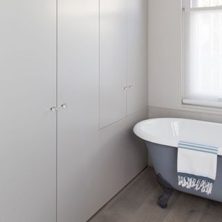 bathroom with bathtub white walls and wooden flooring