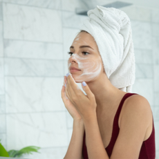 How to cleanse your face - woman washing her face looking in the mirror