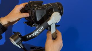 One hand holds the gimbal-mounted camera steady while the other adjusts the balance of the tilt axis