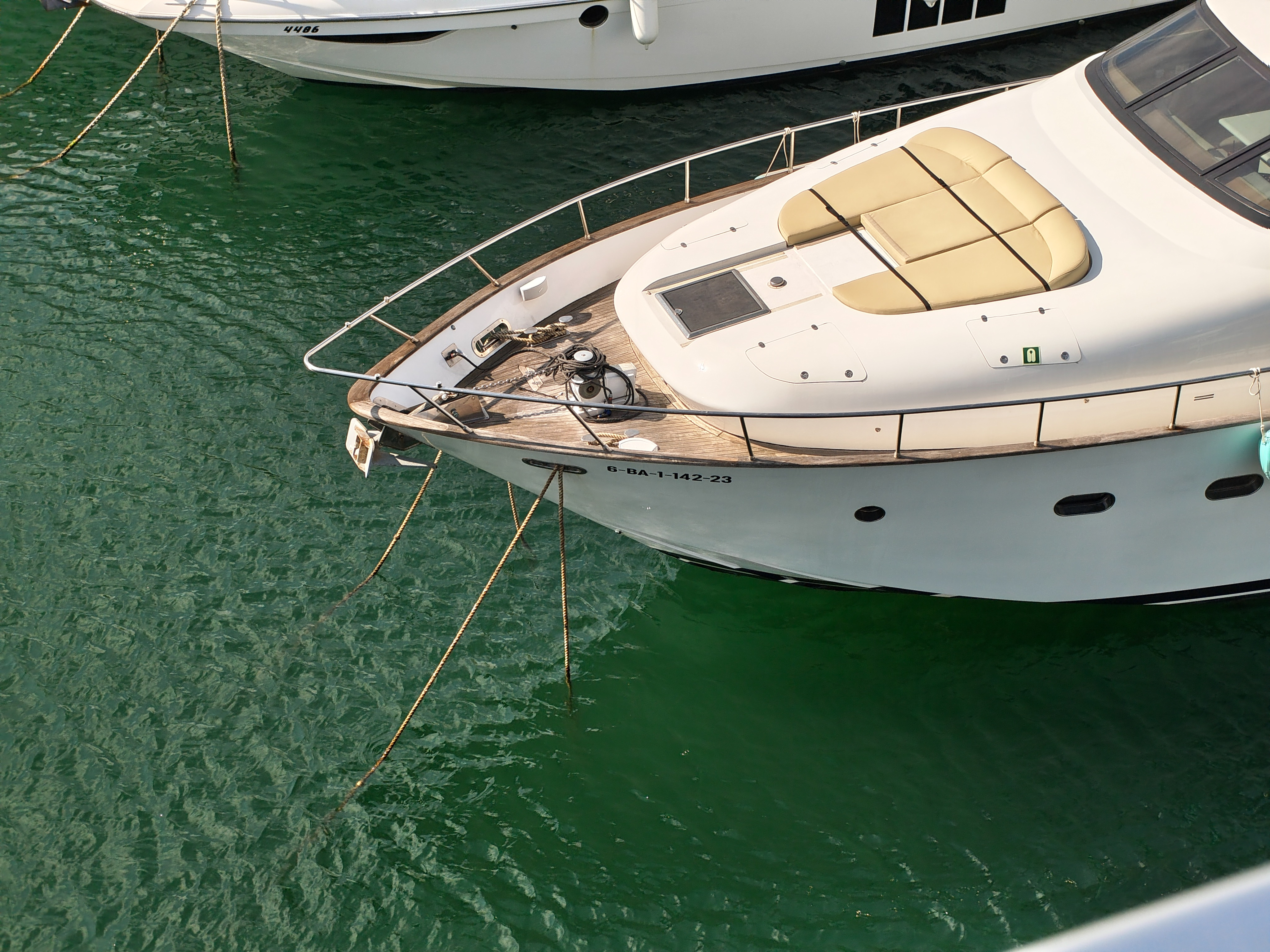 Close-up of a yacht&rsquo;s bow moored in green water with ropes extending to the dock, photographed with the Nothing Phone (4a).