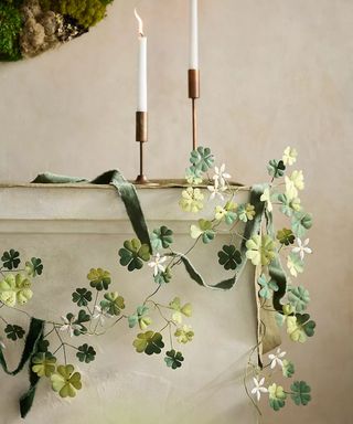 rustic spring mantel shelf decorated with an iron clover leaf garland and candlesticks