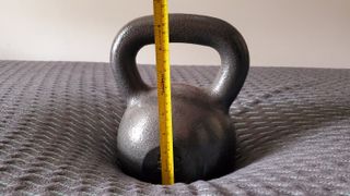 A kettlebell and a tape measure on the Tuft & Needle Mint Hybrid mattress