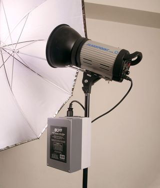 A flashpoint strobe on a light stand with a reflective umbrella