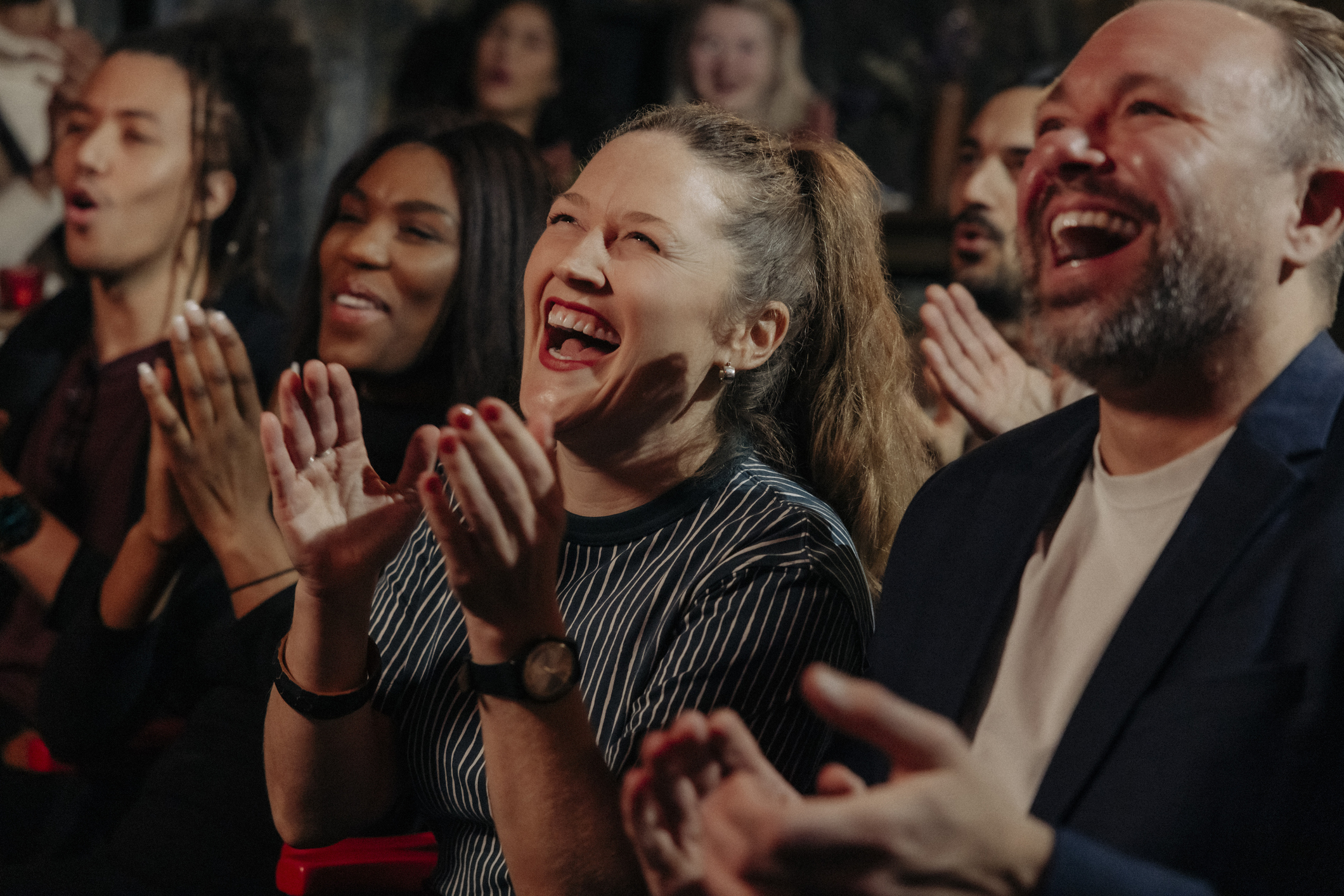 Audience laughing and applauding while watching comedy stage show in theater 
