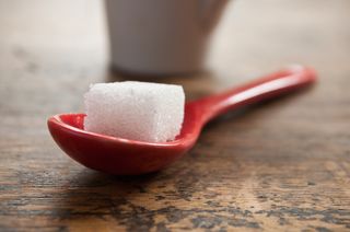 A sugar cube rests on a large spoon