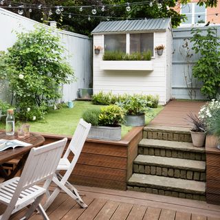 White shed in garden with lawn and decking