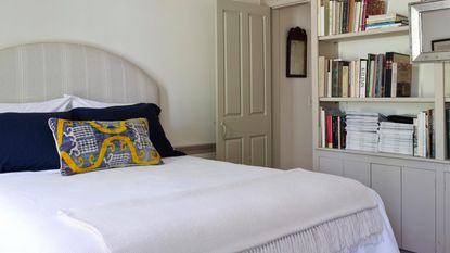 An example of the best mattress for a guest room - a bed with white bedding side angle and book shelf 