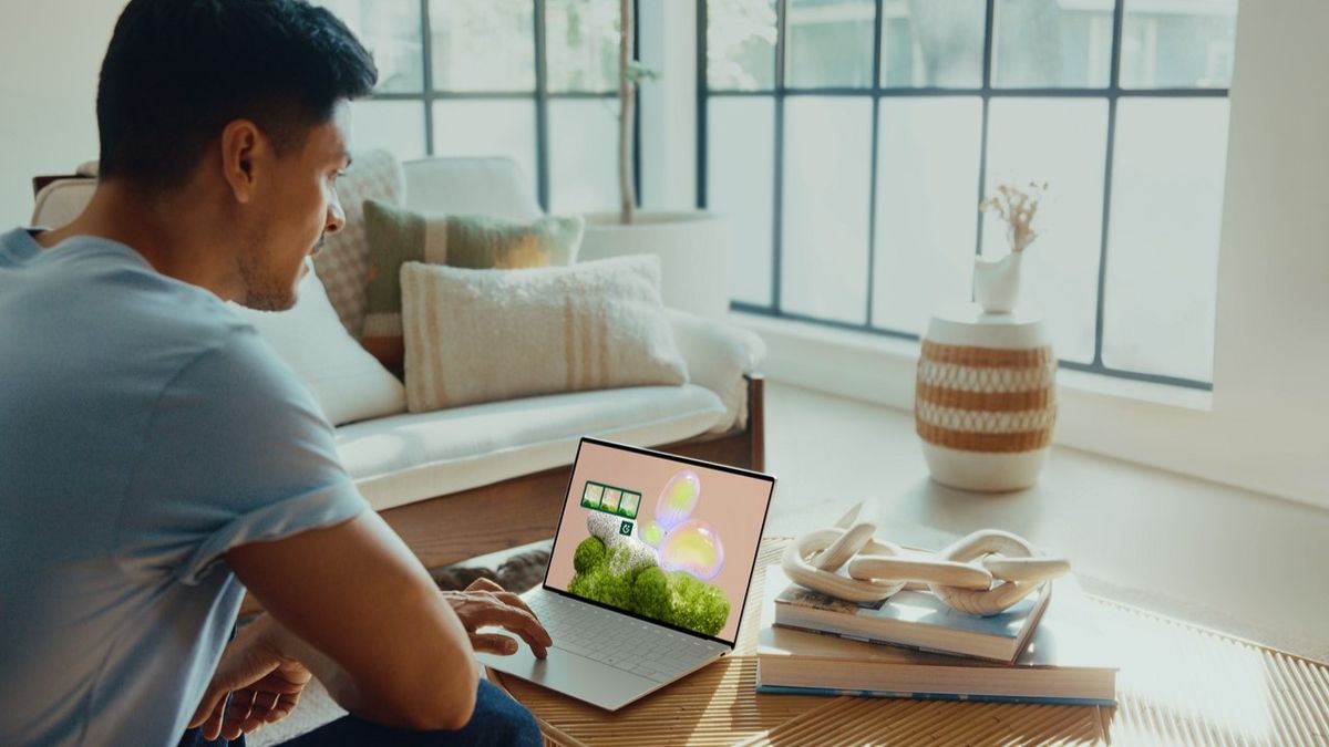 A man sitting at a coffee table using a Dell XPS 13 laptop.