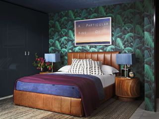 Bedroom with leather bed and tropical leaves wallpaper