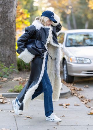 Elsa Hosk wearing a shearling coat, jeans, a baseball cap, The Row's Margaux bag, and a pair of Reebok Classic AZ sneakers.