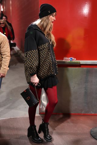 Taylor Swift enters arrowhead stadium in a louis vuitton jacket with a pleated mini skirt and red tights