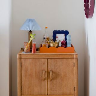 Wooden cabinet console table with orange scalloped tray and decorative display