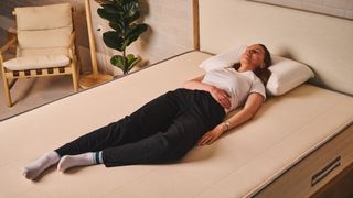 A woman sleeps on her back on the Nolah Natural 11 Mattress