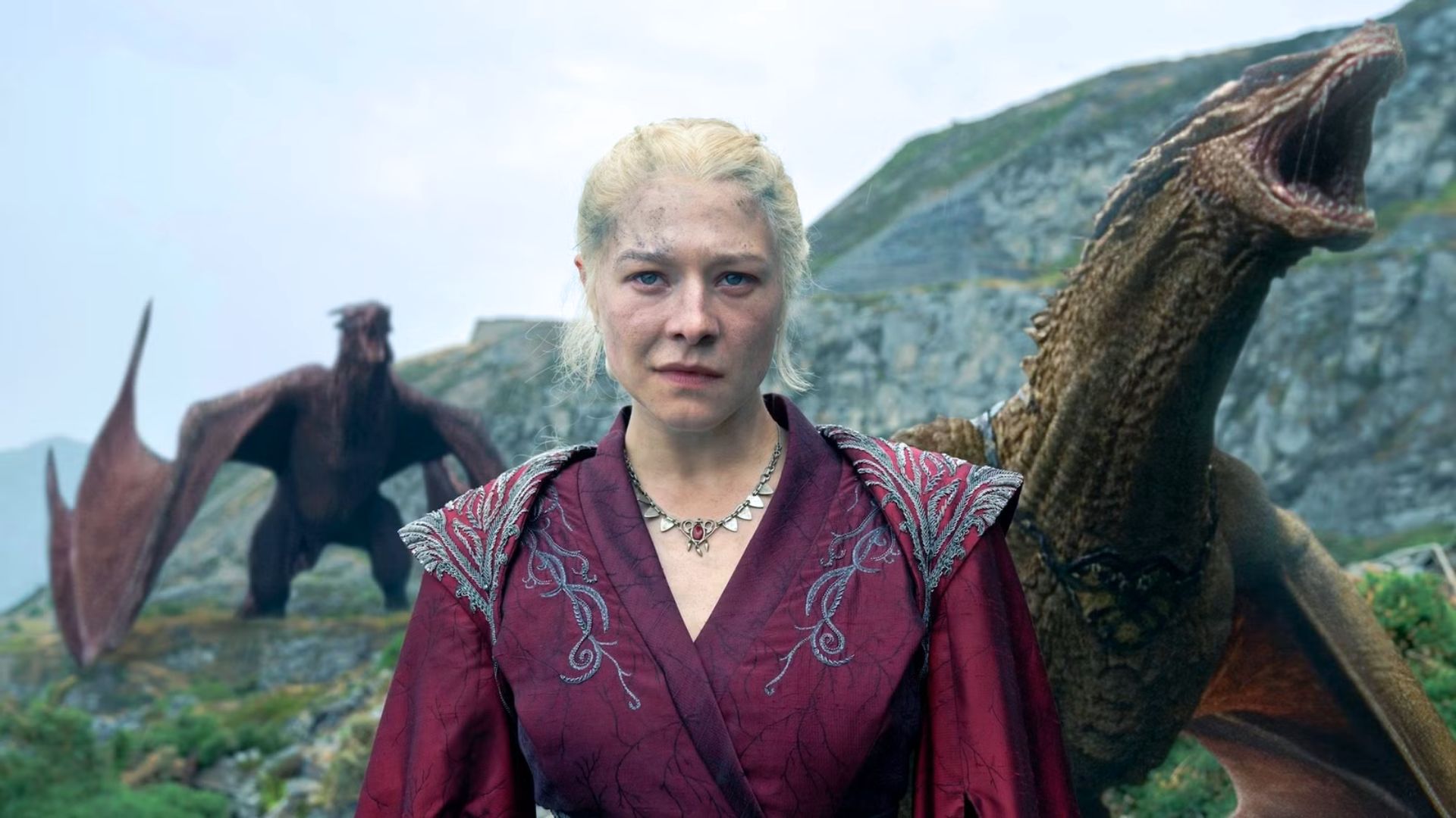 Rhaenyra stands on a cliff in front of two dragons
