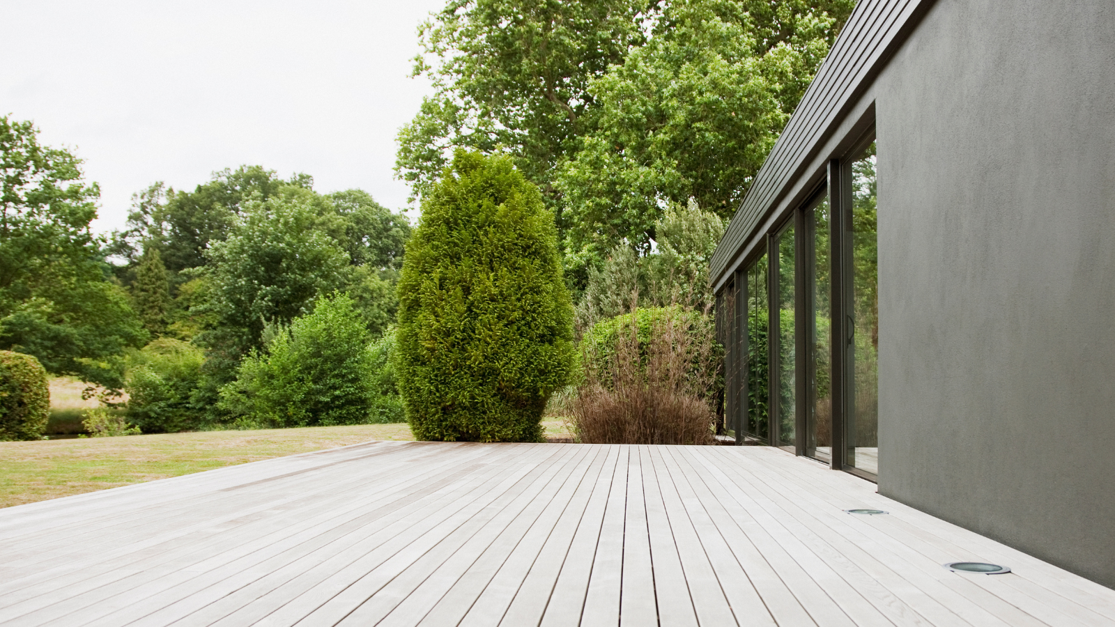 Decking outside a building with lawn and trees in background