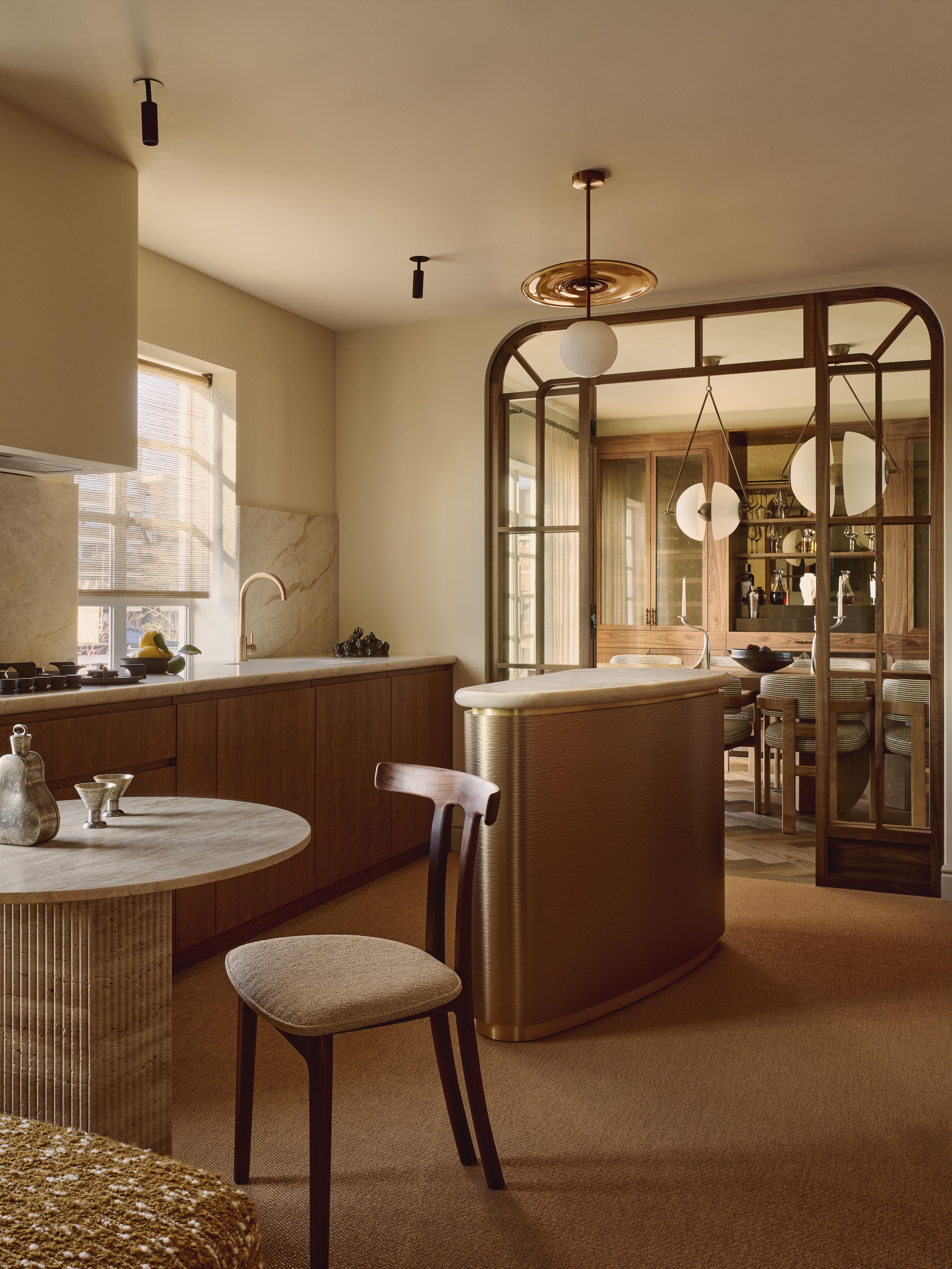 Kitchen area with central oval island, dining table and chair.
